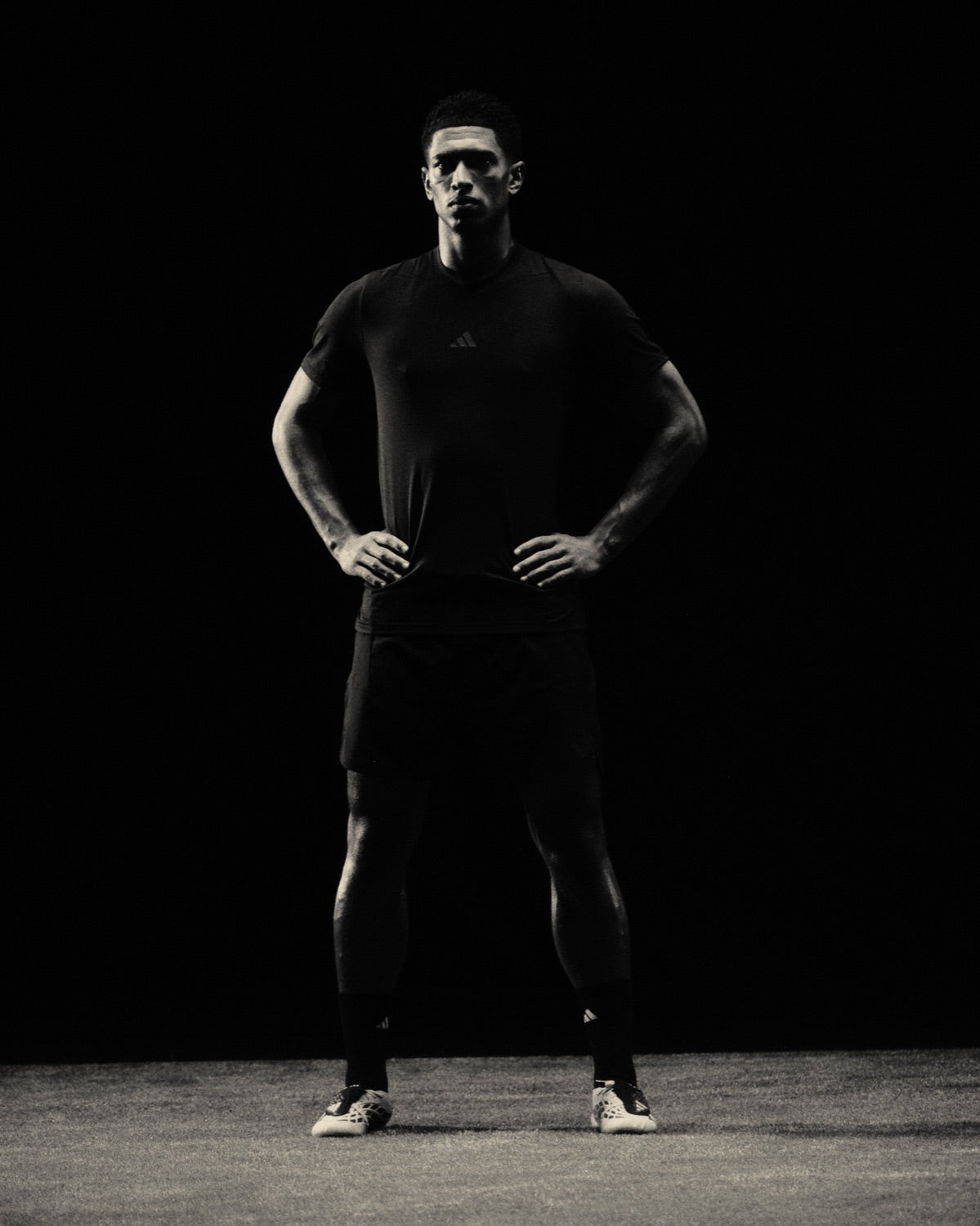 Jude Bellingham standing with hands on hips in a dark studio