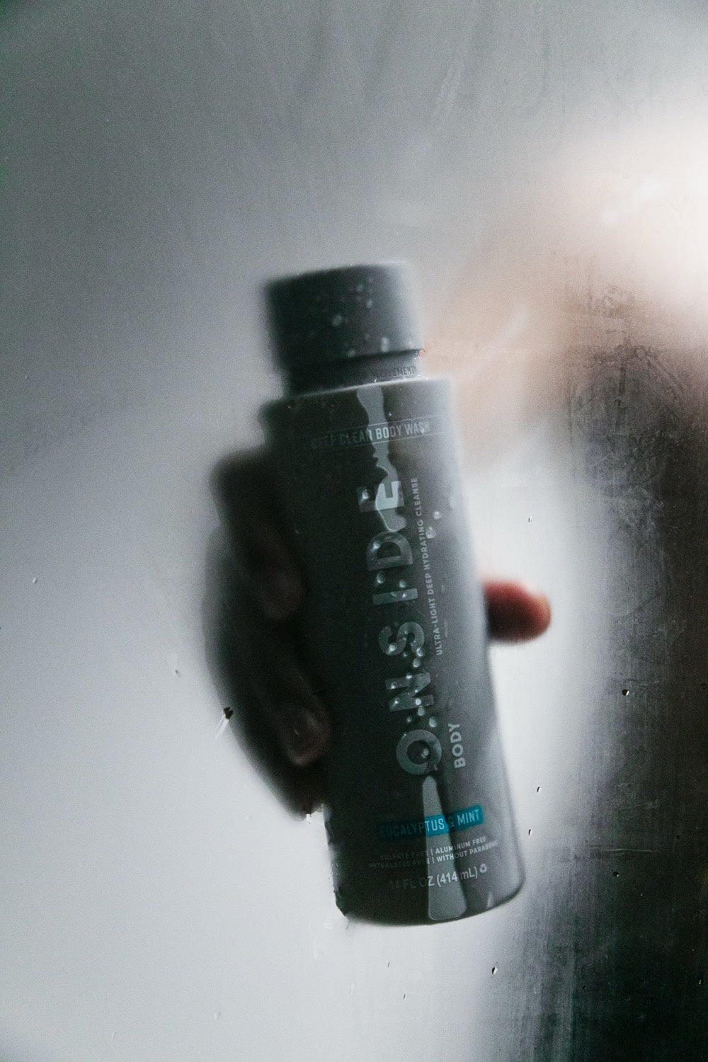 Onside Deep Clean Body Wash held against steamed shower glass