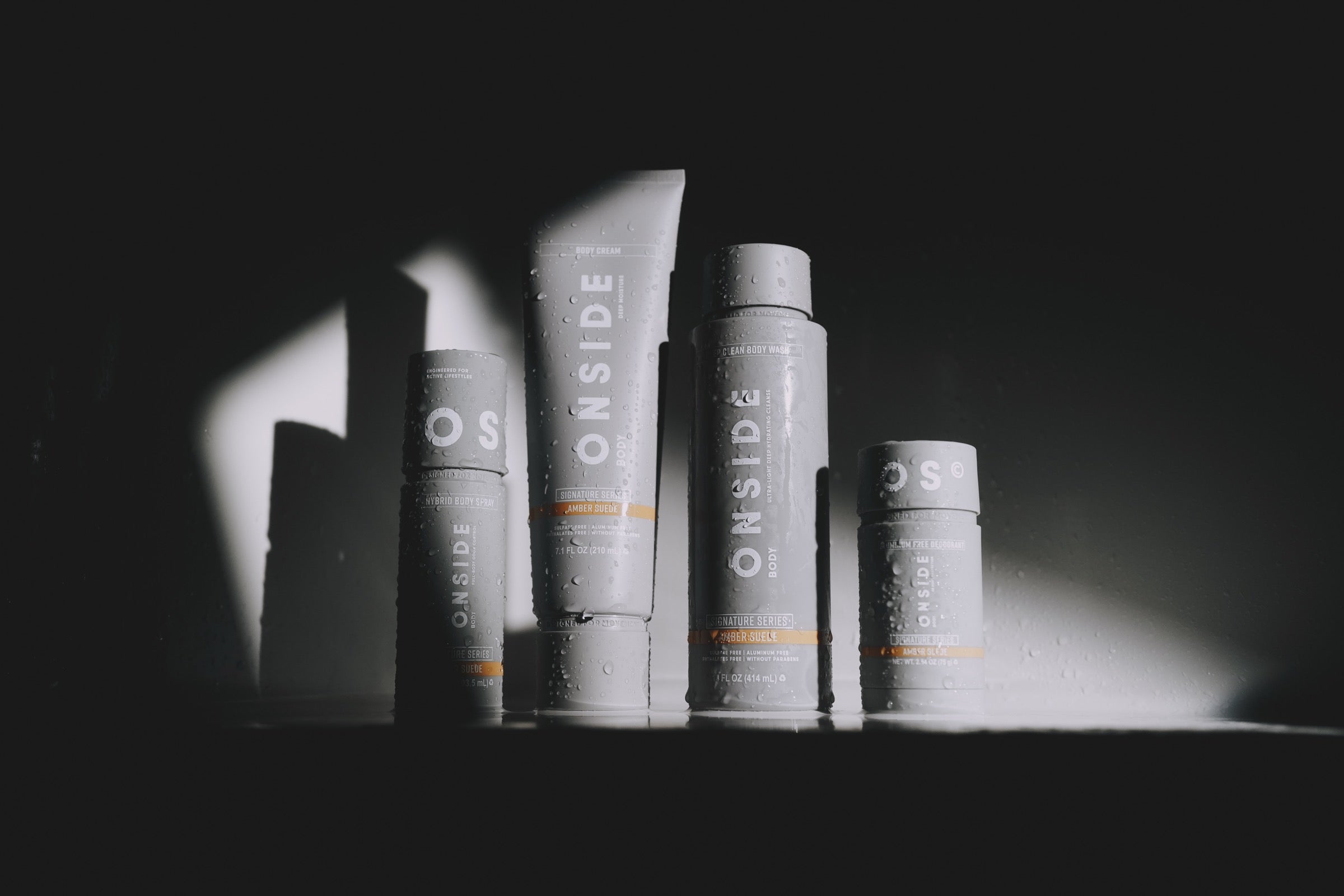 ONSIDE body spray, body cream, body wash and deodorant in a shaft of light